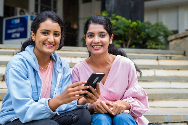 istock Happy smiling students looking at camera while using mobile phone at college campus showing with copy space - concept of technology, education and friendship. 1461631650