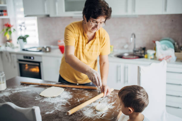 Grandma and grandson are preparing dough for baking in the kitchen