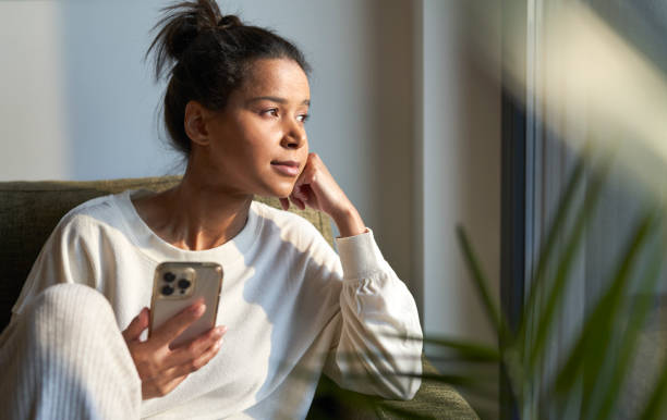 istock Mixed race woman sitting on sofa and using mobile phone 1461634309