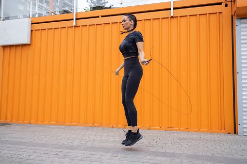 Beautiful caucasian brunette doing rope skips training in the urban area