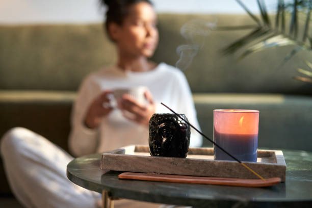 Woman in background preparing for meditation with incense stock photo
