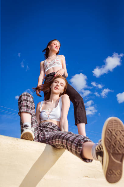istock Summer Concepts. Two Funny Relaxed Girlfriends Posing Together At Stony Wall Against Blue Sky Outdoor. 1461636004
