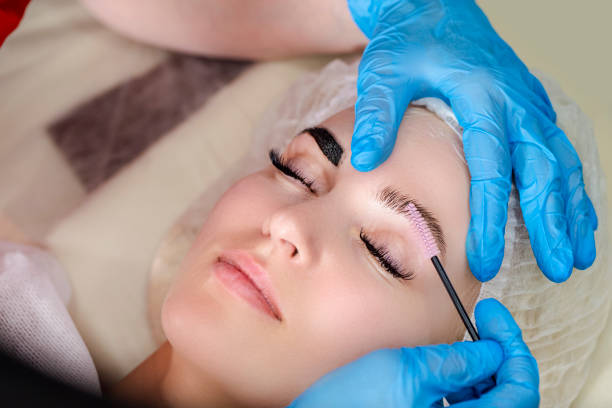 istock Beautician Tattooing Woman's Eyebrows Using Special Equipment During Process of Permanent Make-up Tidying Up Using Brush. 1461636103