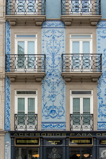 Facade of a restaurant covered in historic azulejos in the historic city center of Porto, Portugal. It used to be a store for writing materials; ink, paper, etc.