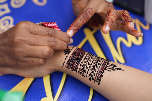 Midsection Of Female Artist Applying Henna Tattoo On A Tourist Hand In Penang, Malaysia