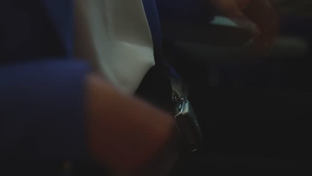 Woman fastens her seat belt in an airplane.