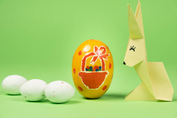 A yellow origami paper Easter bunny and a painted eggs. Easter card, diy with your own hands