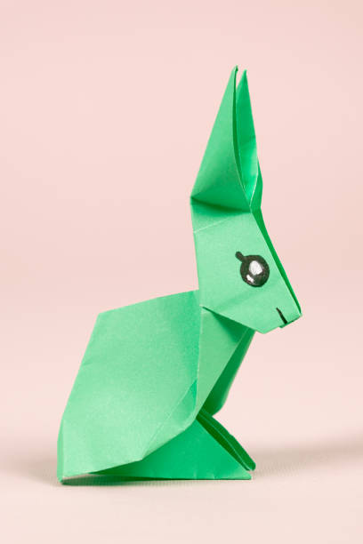 istock A green origami rabbit on a beige background. Crafts for Easter, fold from paper, do it yourself. 1461645078