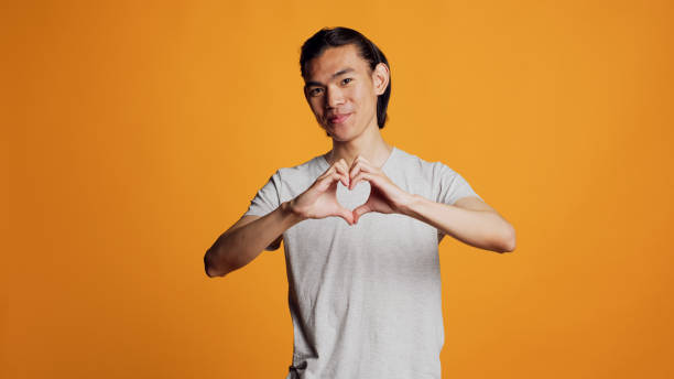 istock Lovely confident guy doing heart shape sign on camera 1461646528