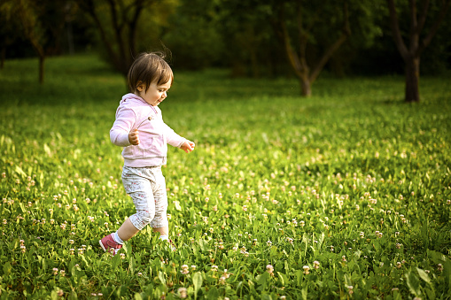 little girl and her first step in a spring lawn.