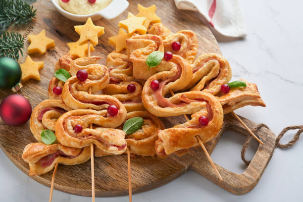 istock Christmas or New Year appetizer. Christmas tree shape puff pastry buns with cheese and ham. Group of Christmas tree shapes on wooden board. Festive idea for Christmas or New Year dinner. Top view. 1461649409
