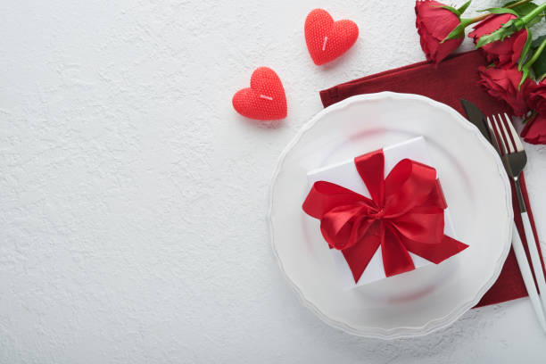 istock Valentines day romantic table setting. Empty or closeup of a dinner black plate, knife, fork and decorative silk hearts on white background. Holiday concept. Copy space for inscriptions. 1461651032