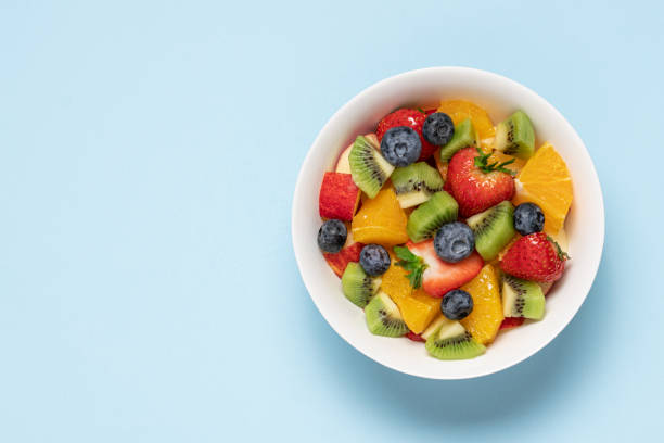 tazón con ensalada de frutas sobre fondo azul - tazón para frutas fotografías e imágenes de stock