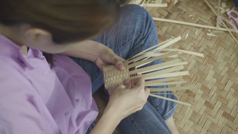 Asian Woman weaving a dry leave for weaving making basket