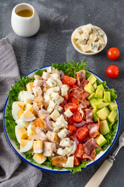 istock Tradition Cobb salad with fried chicken, avocado, fresh tomatoes, eggs, bacon and cheese on a plate on a dark background. Top view, copy space, selective focus 1461661971