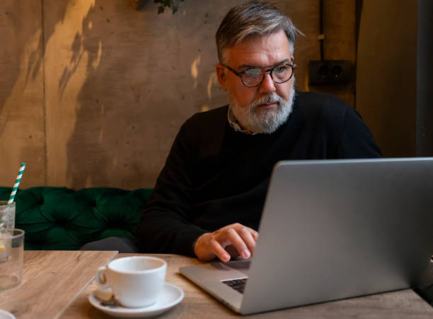 istock Mature businessman working on laptop at cafe 1461663934