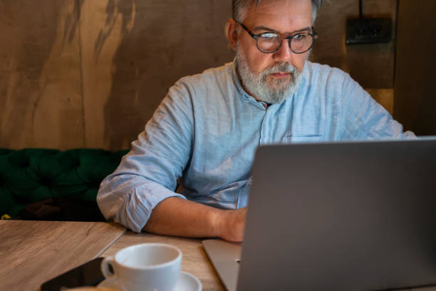istock Mature businessman working on laptop at cafe 1461663988
