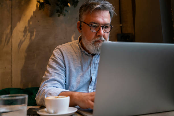 istock Mature businessman working on laptop at cafe 1461664110