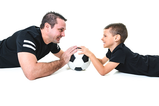 A Young man and a boy with a soccer ball isolated on white background