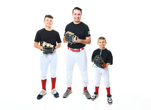 A teen and brother baseball player with dad on Studio shot over white.