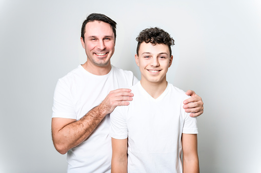 A father with adorable teen son isolated on white