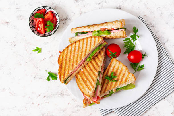 istock Club sandwich panini with ham, tomato, cheese and lettuce. Top view 1461666098