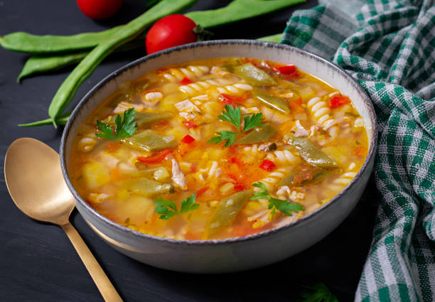 istock Minestrone, italian vegetable soup with pasta on black table. 1461666191