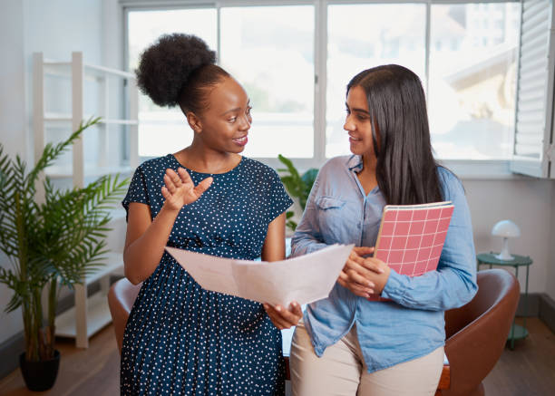 Two women discuss work solutions in boardroom office, mentorship learning stock photo