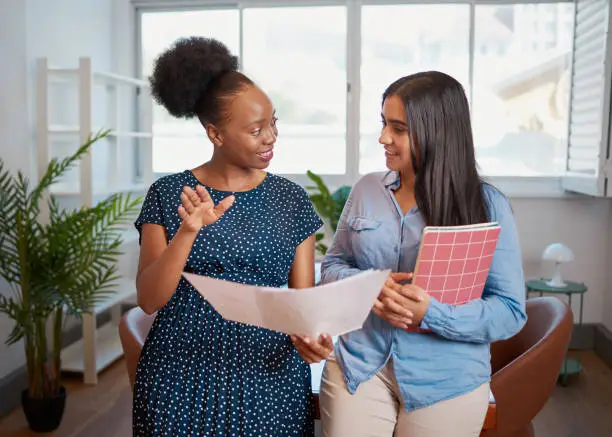 Photo of Two women discuss work solutions in boardroom office, mentorship learning