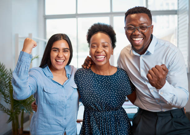 Three business people celebrate successful achievement in office cheer laugh stock photo