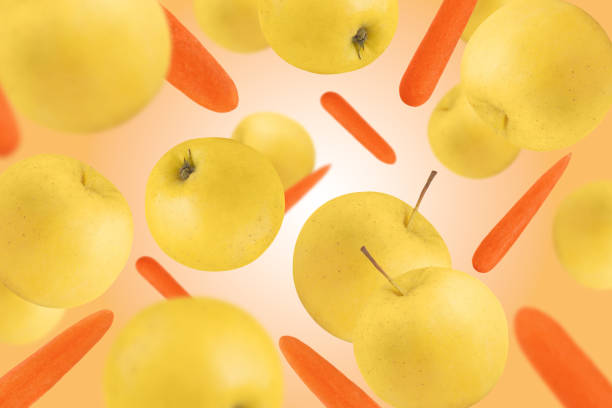 Levitation of apples and carrots on an orange background.