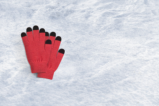 Red winter gloves on a snow background