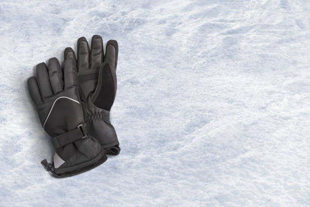 istock Black snow gloves on a snow background 1461670008