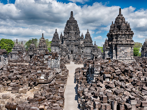 A path winds through ancient stone blocks towards the central tower at the ancient Buddhist temple of Candi Sewu in Yogyakarta.
