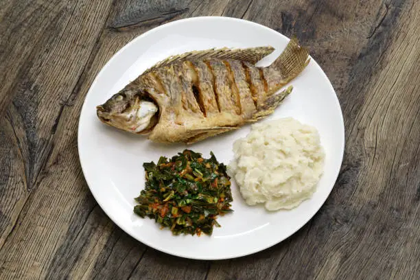 Photo of fried fish(Tilapia), ugali(white maize flour mash) and Sukuma Wiki(kale stew), Kenyan food