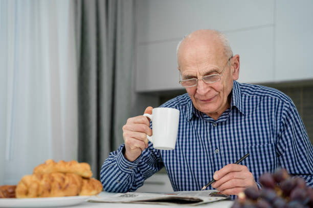 istock Concentrated elder man wearing eyeglasses solving crossword 1461671855