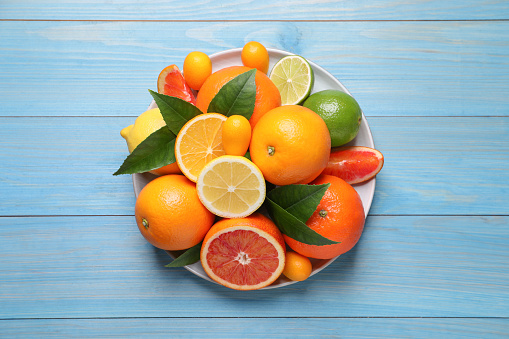 Different citrus fruits on light blue wooden table, top view