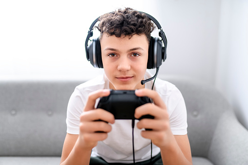 A Portrait of boy playing videogames on tv at vacation, sits at home on the cozy couch