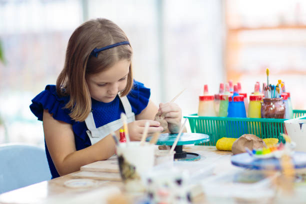Child at pottery wheel. Kids arts and crafts class