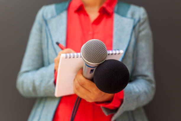 Media journalist at news conference, writing notes, holding microphone stock photo