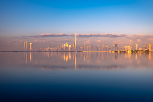 Dubai city skyline from distant with water reflection during sunset sunrise