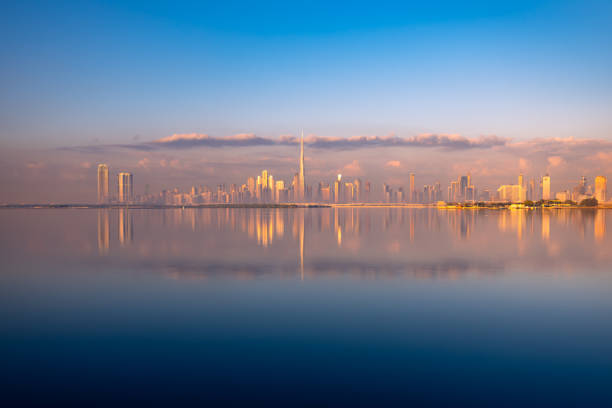 Dubai city skyline from distant with water reflection during sunset sunrise Dubai city skyline from distant with water reflection during sunset sunrise khalifa stock pictures, royalty-free photos & images