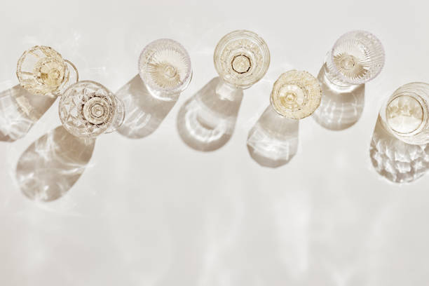 top view white sparkling wine in different glasses of wine, stemmed glass with sun shadow and glare on light beige background. white wine tasting concept flat lay, copy space. summer drinks - nobody alcohol champagne wine imagens e fotografias de stock