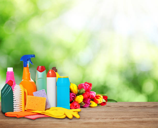 istock Different cleaning supplies and spring flowers on wooden table outdoors, space for text 1461681703