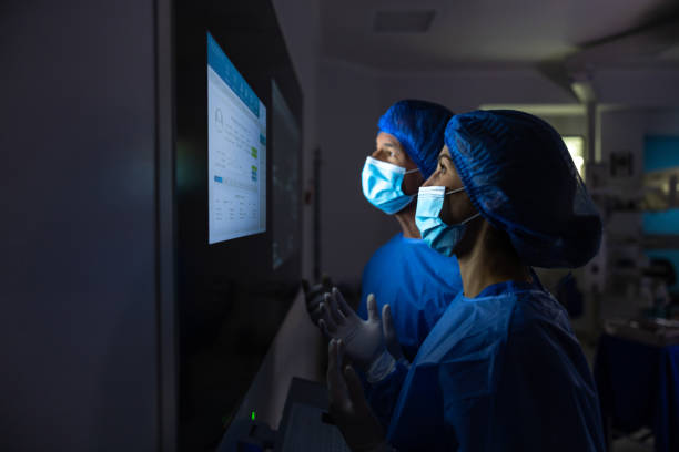 lekarze patrzą na wyniki badań medycznych na monitorze na sali operacyjnej - surgeon doctor operating room emergency room zdjęcia i obrazy z banku zdjęć