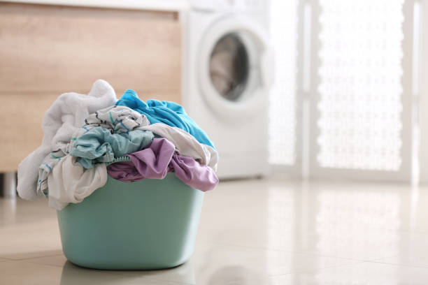 istock Plastic basket with dirty clothes on floor in bathroom. Space for text 1461681825