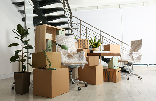 Cajas de cartón y muebles cerca de escaleras en la oficina. Día de mudanza photo
