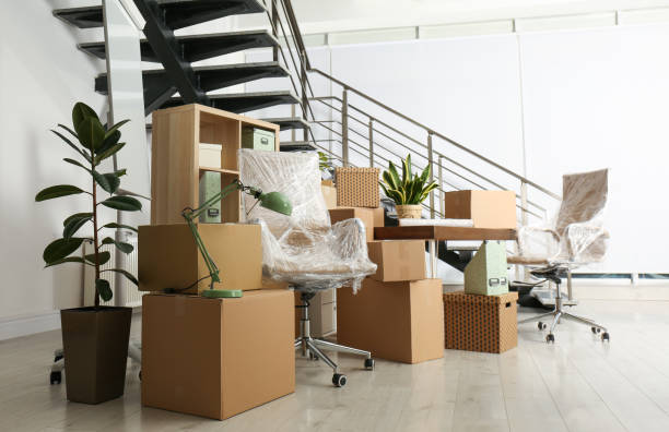 Cardboard boxes and furniture near stairs in office. Moving day stock photo