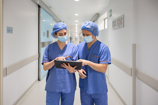 Team of Latin American doctors using a tablet computer while working at the hospital