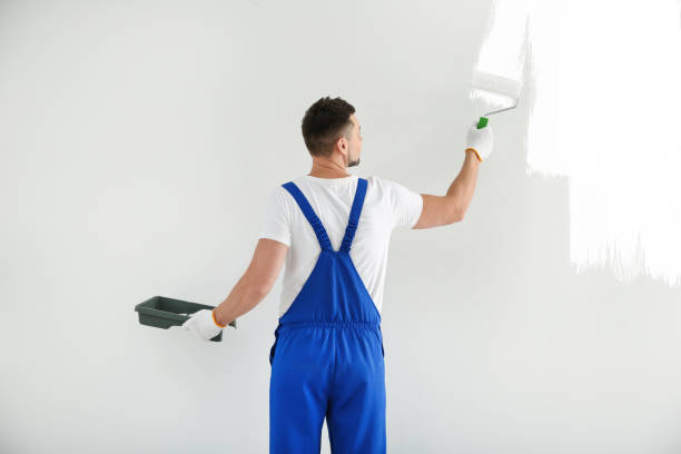 istock Man painting wall with white dye indoors, back view 1461683077